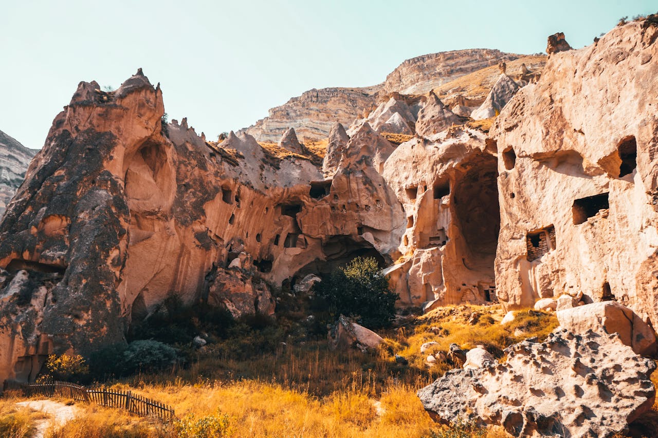 Explore the historic cave formations and rocky landscape of Cappadocia, Turkey, bathed in warm sunlight.